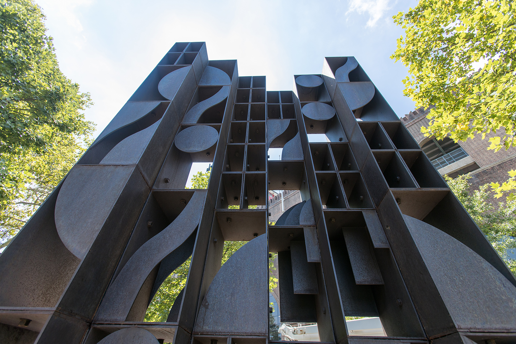 Atmosphere and Environment - bronze geometric Louise Nevelson sculpture with trees around it