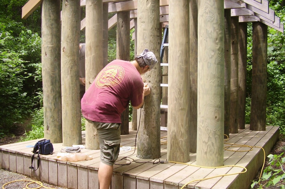 A conservator restoring Ed Levine’s <em>Embodying Thoreau: dwelling, sitting, watching</em> in Pennypack Park. Photo © Association for Public Art.