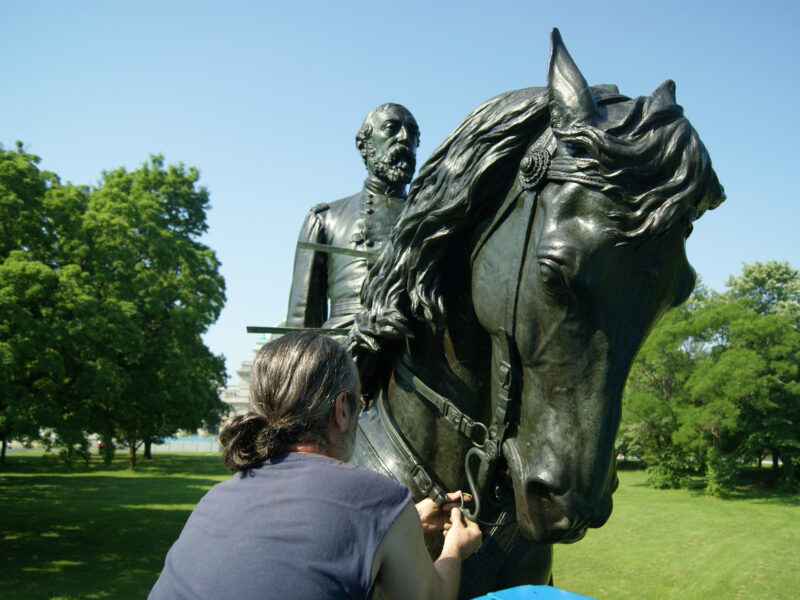 A conservator installs new horse reins for the bronze General Meade equestrian sculpture in Fairmount Park