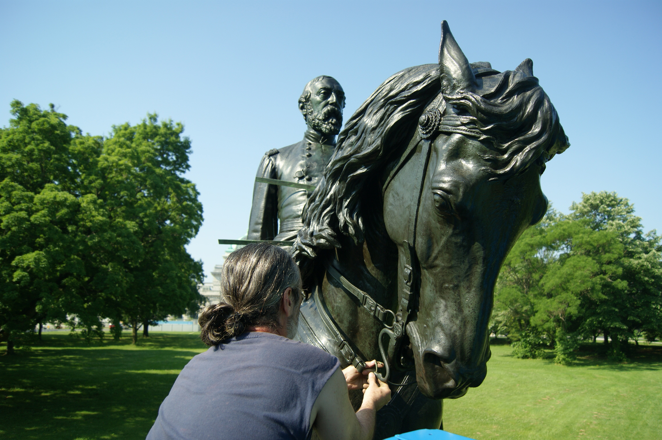 A conservator installs new horse reins for the bronze General Meade equestrian sculpture in Fairmount Park