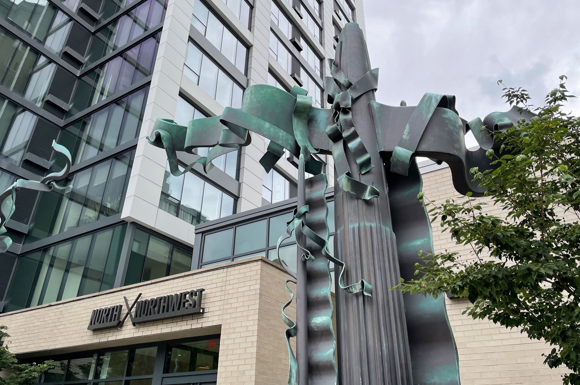 Close-up of Albert Paley’s steel sculpture at a building entrance: two tall columns are wrapped with banner and ribbon shapes that seem to be fluttering in the breeze