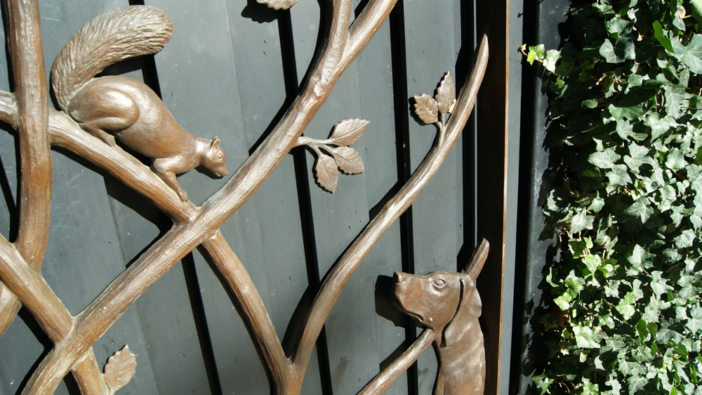 A detail of a squirrel and a dog on the Gardener's Cottage Gates