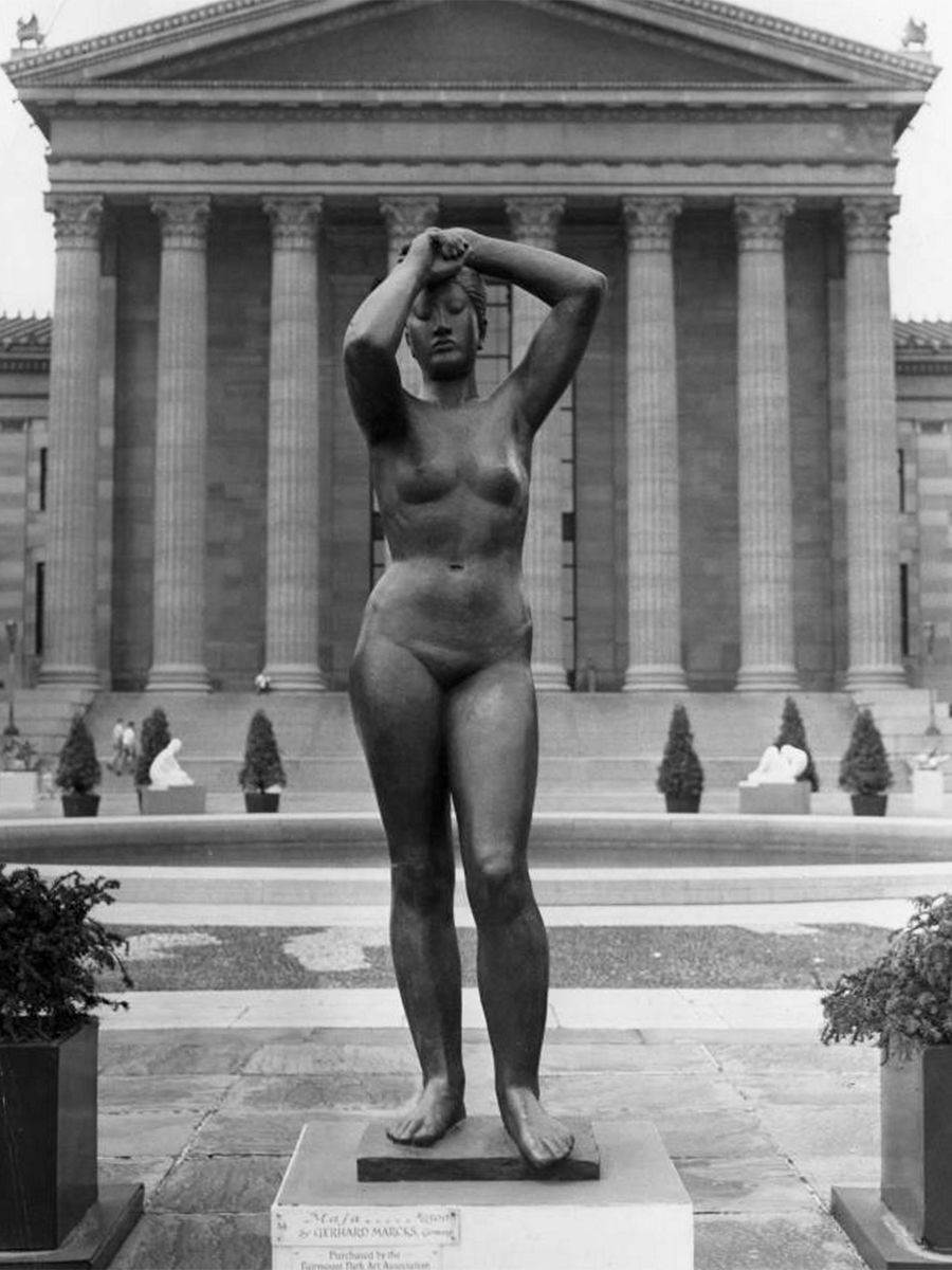 A black and white photograph of the Maja sculpture, a nude female figure with arms lifted over head and one leg bent.