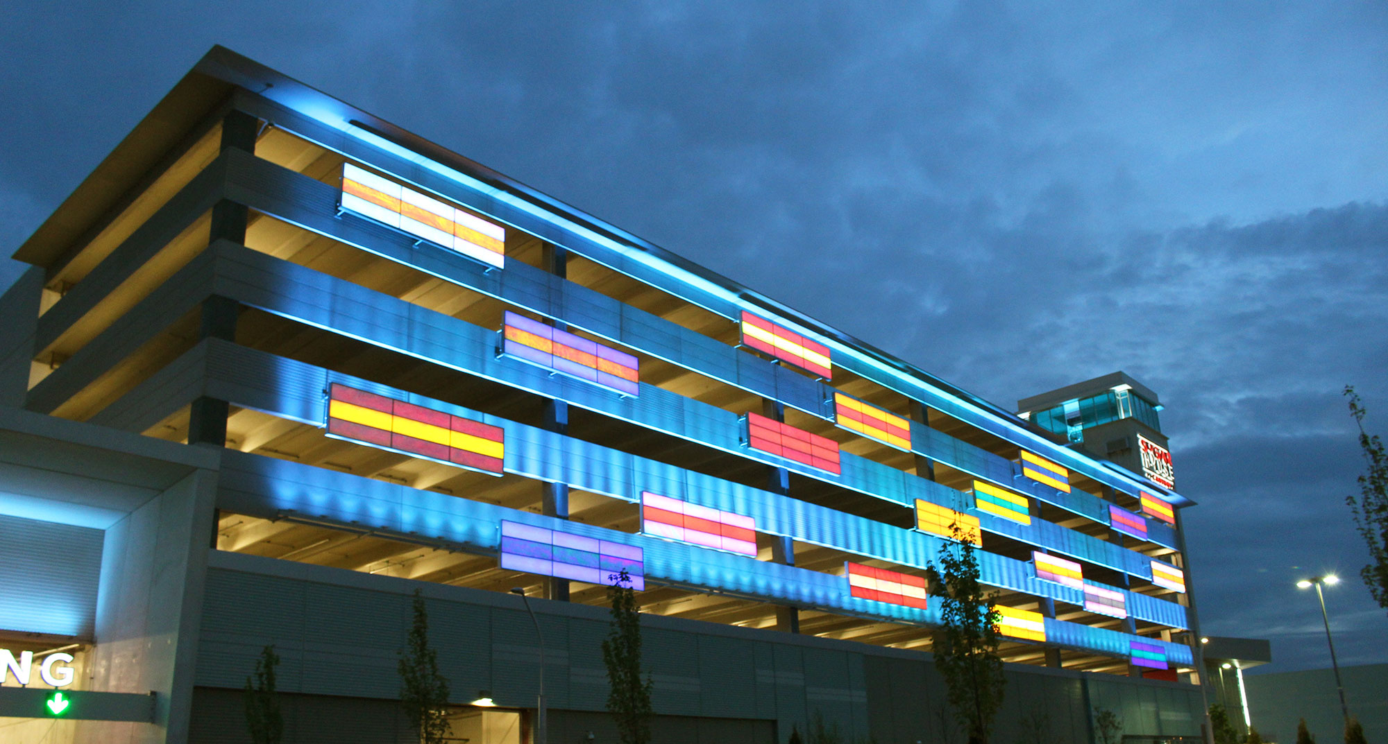 Colorful illuminated panels along a 7-story parking garage at night