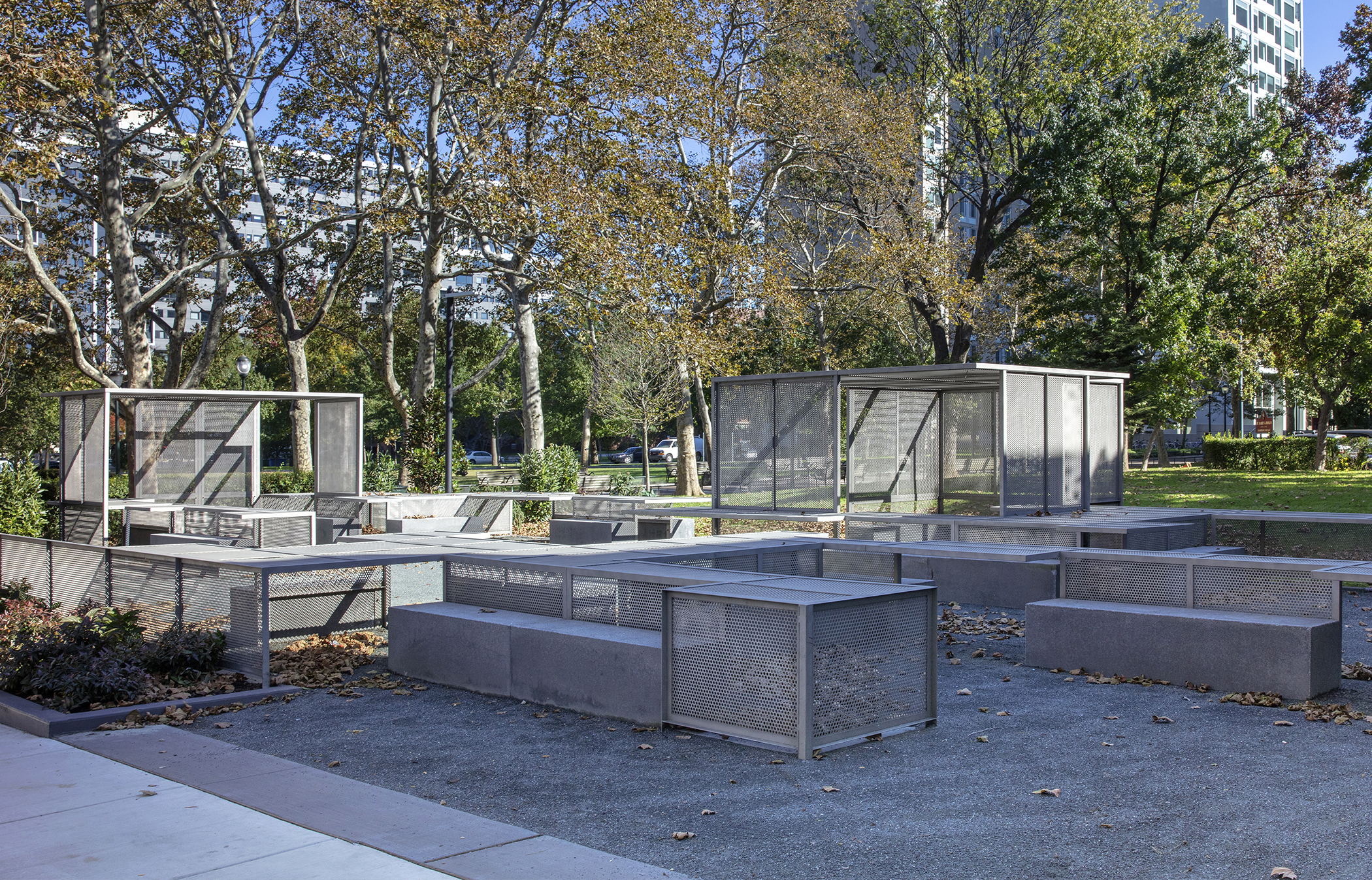 A series of puzzle-like perforated gray steel pavilions, tables and benches