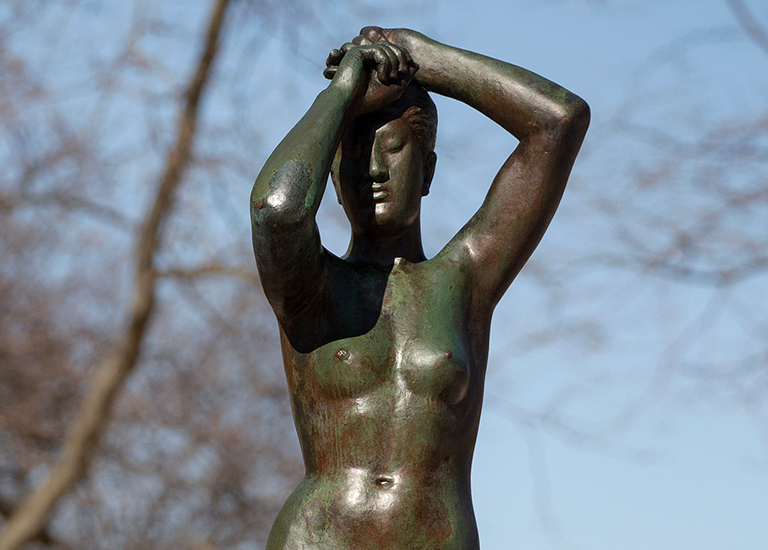 Gerhard Marcks' bronze Maja sculpture on a sunny day - female nude, arms raise overhead