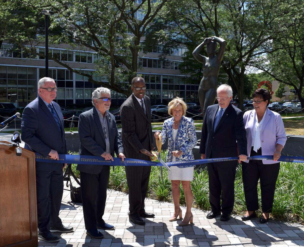 Philadelphia Mayor Kenney and other community representatives cut an official ribbon with giant scissors to formerly open "Maja Park" to the public. The figurative female nude sculpture, "Maja," stands in the background 