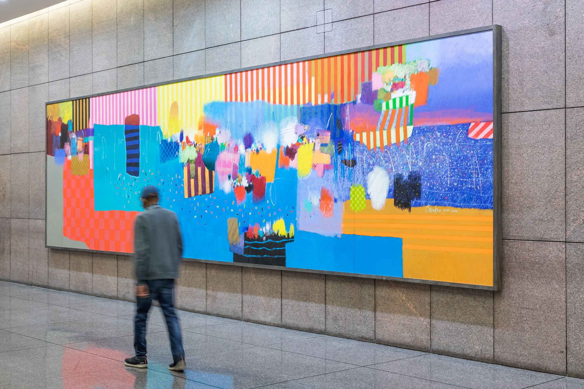 The artist, Moe Brooker, walking in front of his brightly-colored, abstract, 30-foot-long painting, "The Fruit oThe artist, Moe Brooker, standing in front of his brightly-colored, abstract, 30-foot-long painting, "The Fruit of the Spirit", during installation in the Green Federal Building Lobbyf the Spirit", during installation in the Green Federal Building Lobby