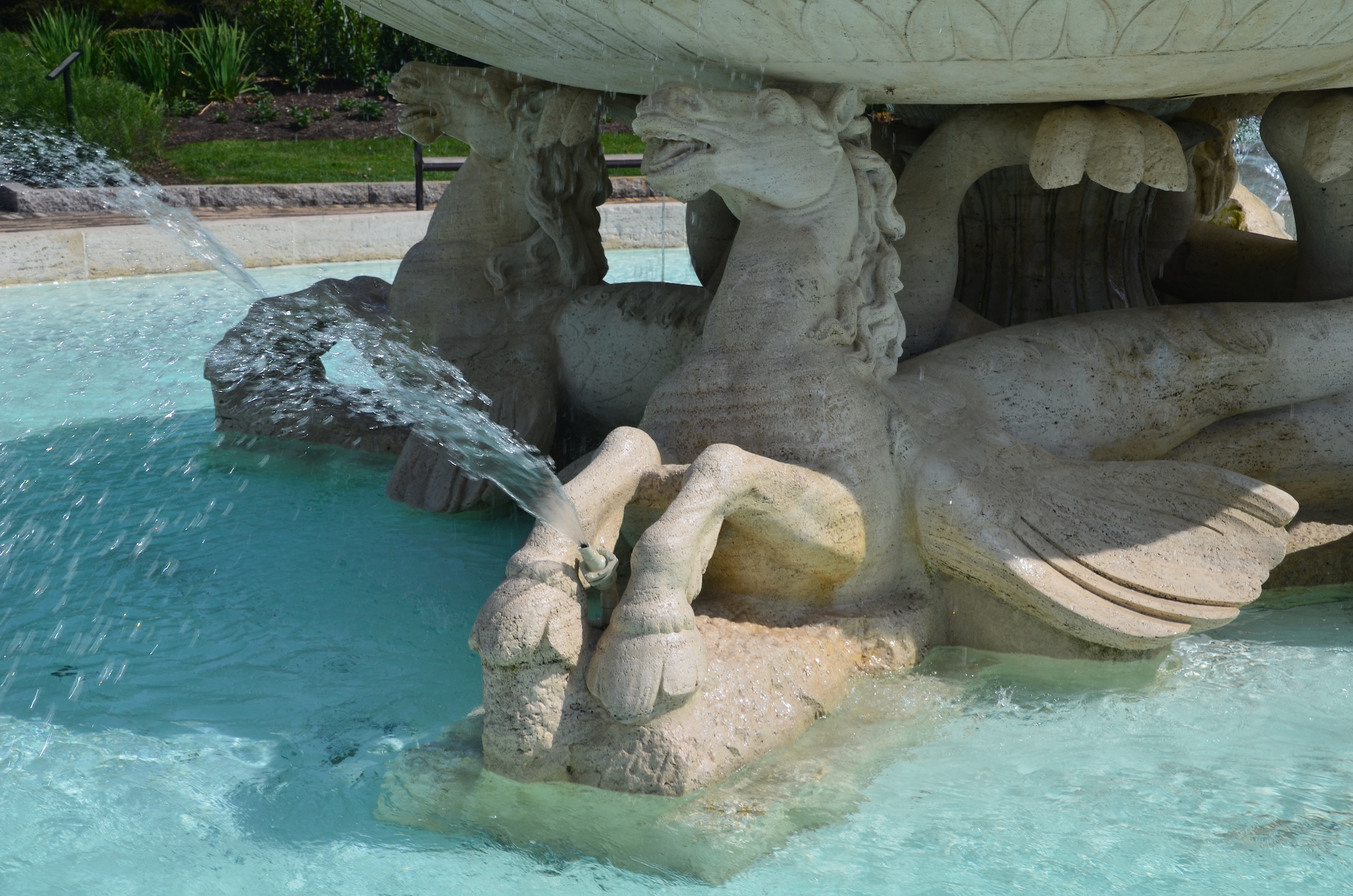 Close-up of a light colored stone (travertine) outdoor fountain with four winged horses