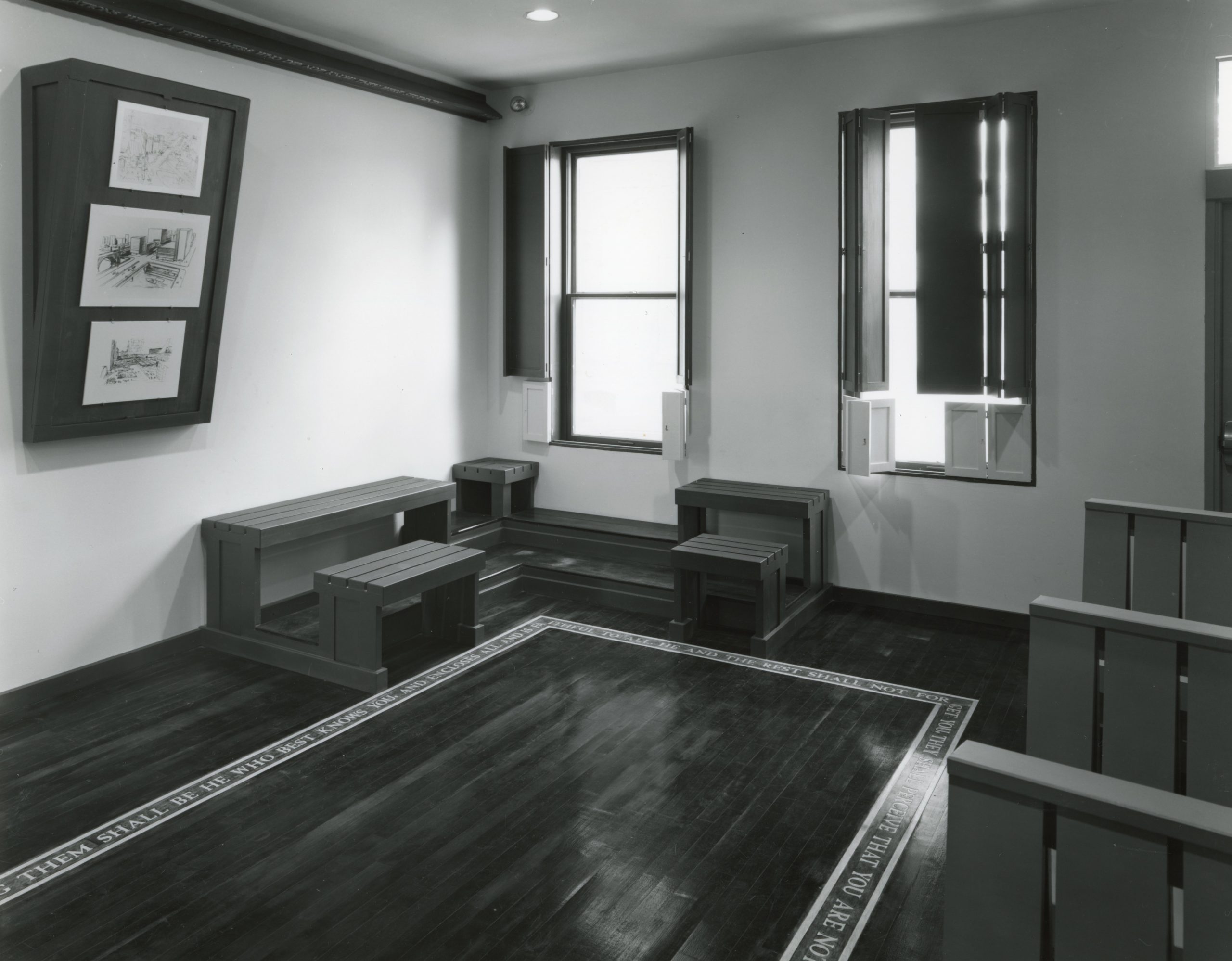 Black and white photograph of Siah Armajani's "Louis Kahn Lecture Room" installation, which resembles a Quaker meeting house and lecture hall. 
